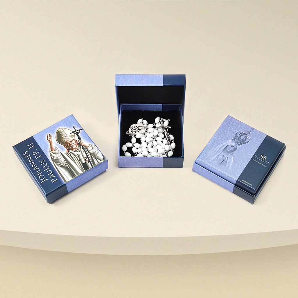 A replica of the Rosary given by the Holy Father, displayed in an open box with a personalized lid featuring an image of Saint John Paul II, and an additional closed box beside it.